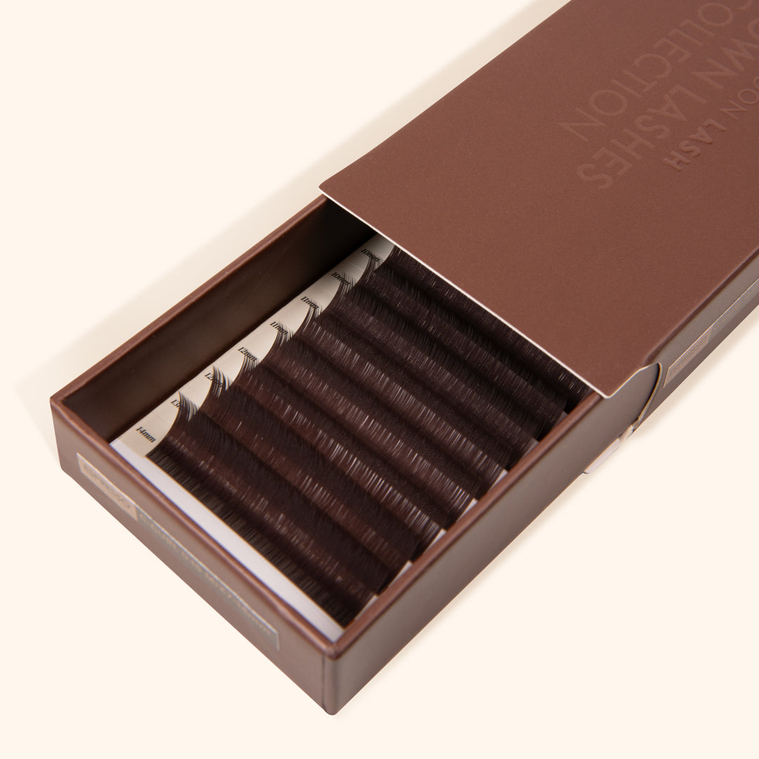 half opened brown paper lash tray with dark brown eyelash extension inside 