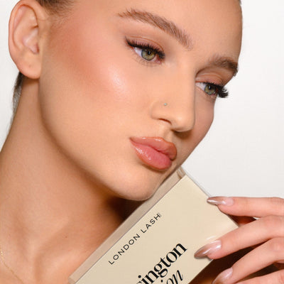 Woman holding a 'Kensington Collection' makeup product with a neutral background